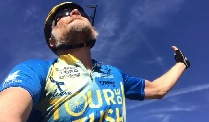 Dave Klein in a Tour de Tush bike jersey looking up at a blue sky