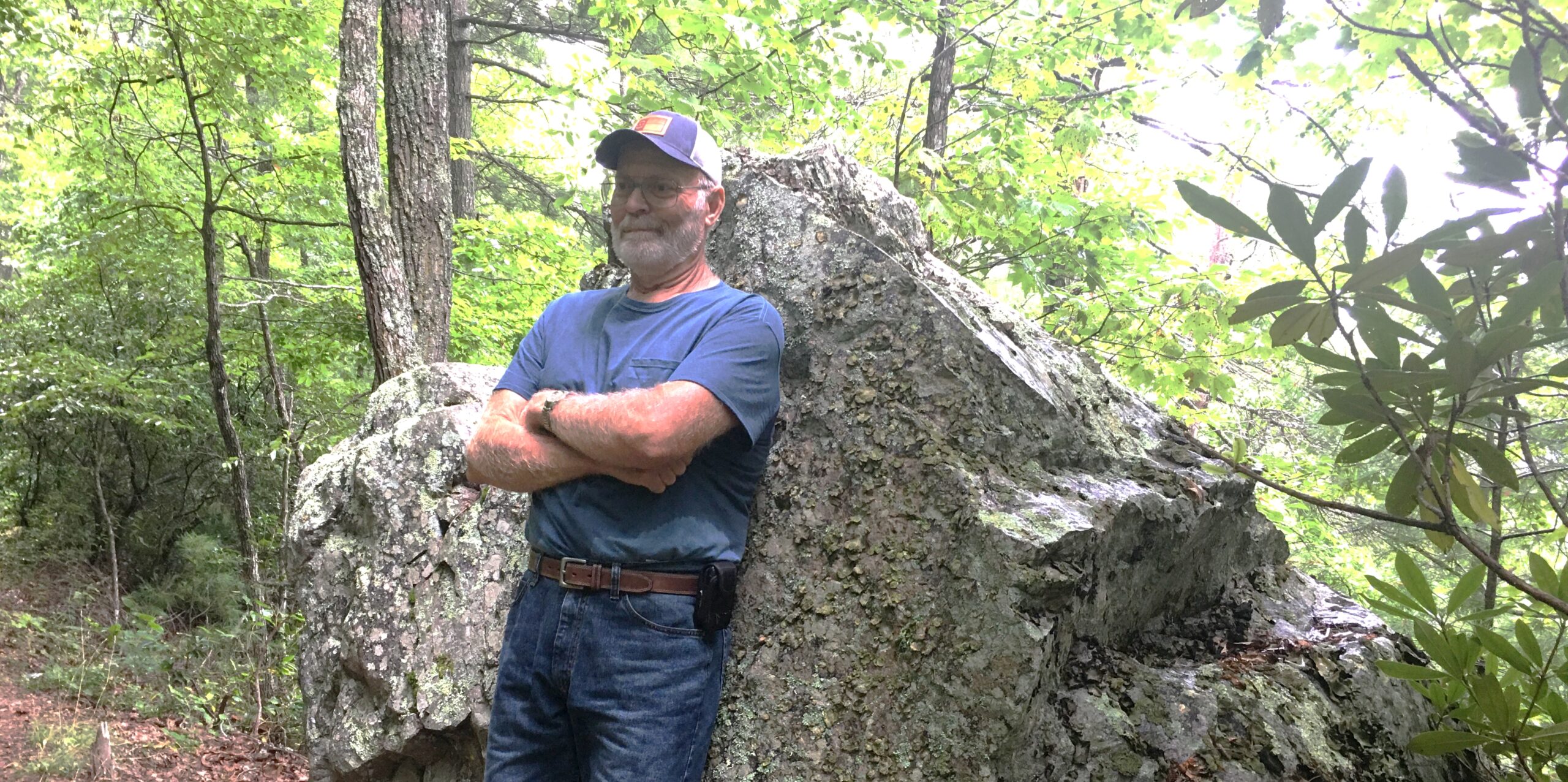 Glenn Honeycutt stands smiling in the forest.