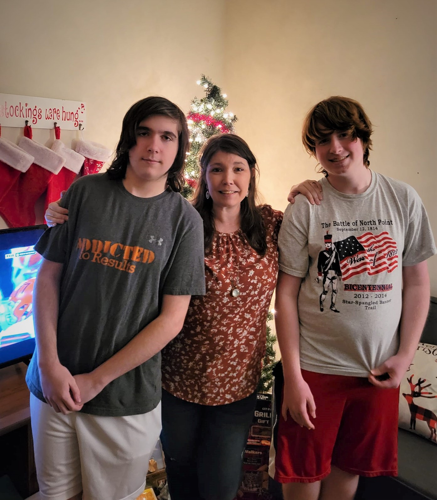Shilo with her two kids posing during the holidays with football on in the background