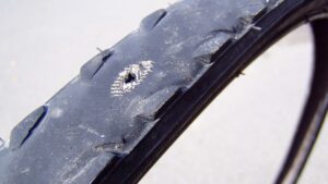 A picture of a worn down bike tire with the casing, a nylon mesh, poking through.