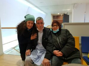 Yasmina stands next to her father, who is sitting between her and her mother. 